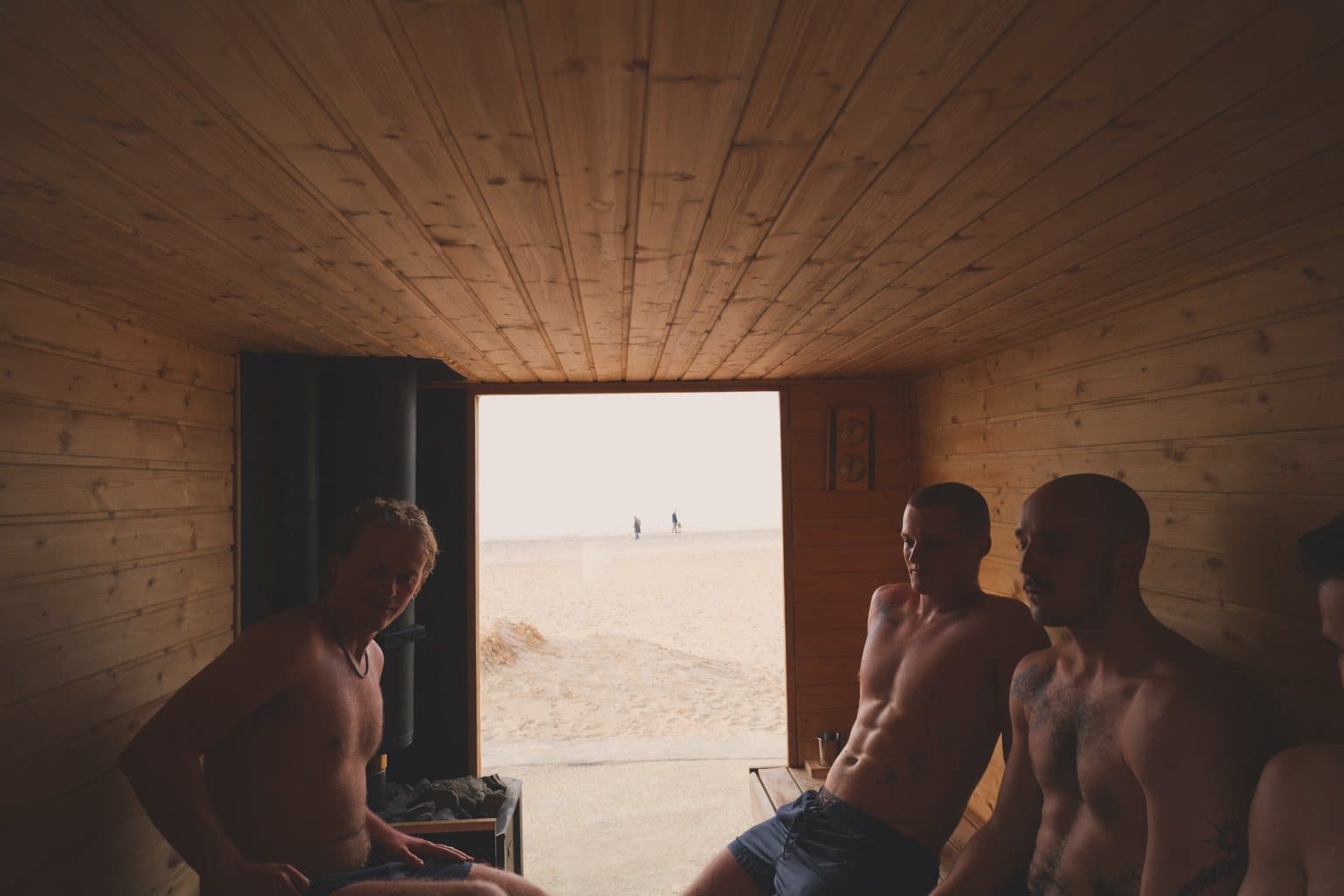 Gæster i saunaen med døren åben ud mod stranden